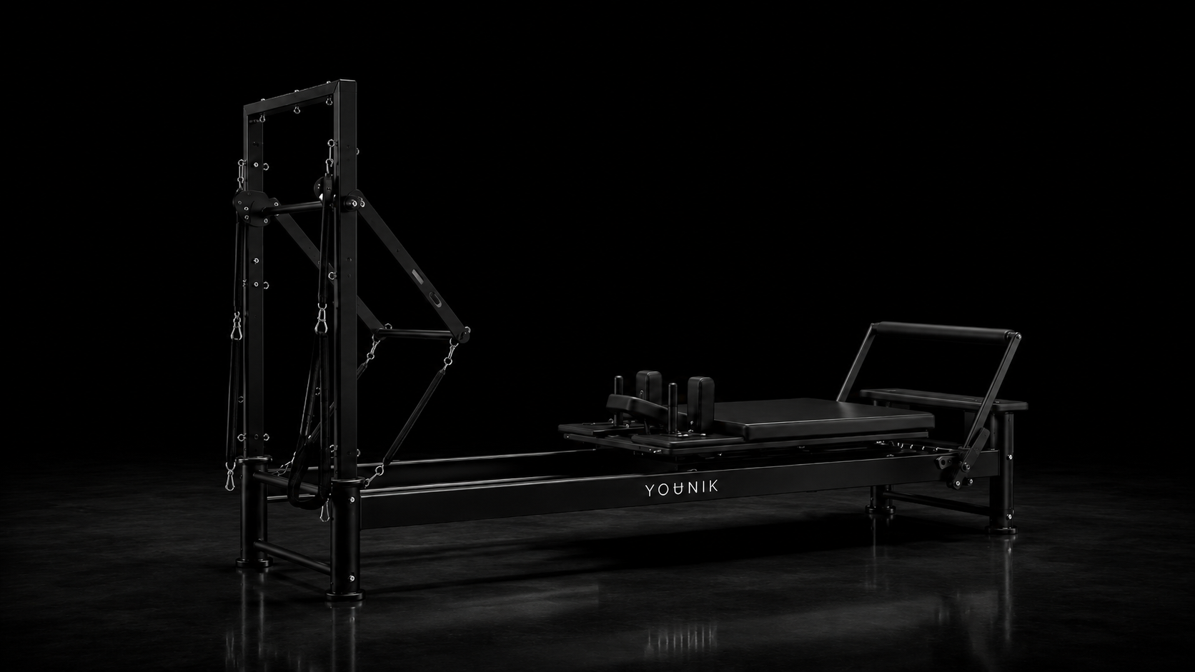 YOUNIK V5 Reformer z boku pod úhlem v tmavém studiu